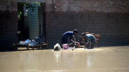 Des hommes dans une rue inondée de Charsadda, au Pakistan, dimanche 28 août 2022.&nbsp; (HUSSAIN ALI / ANADOLU AGENCY / AFP)