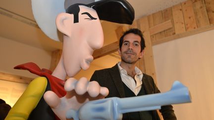 Le nouveau scénariste de la série Lucky Luke pose à côté du célèbre cow-boy solitaire le 28 janvier 2016 à Angoulême. (GEORGES GOBET / AFP)