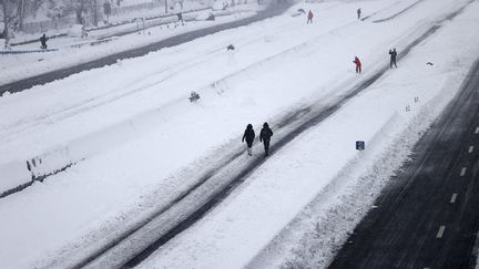 Des personnes marchent le long de l'autoroute M-30, à Madrid, le 9 janvier 2021. (BURAK AKBULUT / ANADOLU AGENCY / AFP)