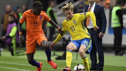 Le Néerlandais Quincy Promes (à gauche) au duel avec le Suédois Emil Forsberg (à droite) sous les yeux de l'entraîneur des Oranje, Danny Blind, lors du match nul entre les deux équipes (1-1) le 6 septembre dernier à Solna, dans la banlieue de Stockholm.  (PONTUS LUNDAHL / TT NYHETSBYR?N)