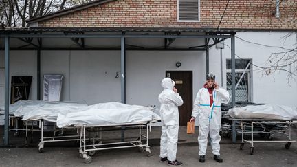 Des médecins&nbsp;près de corps de victimes dans une morgue de Boutcha, près de Kiev (Ukraine), le 19 avril 2022. Photo d'illustration. (YASUYOSHI CHIBA / AFP)