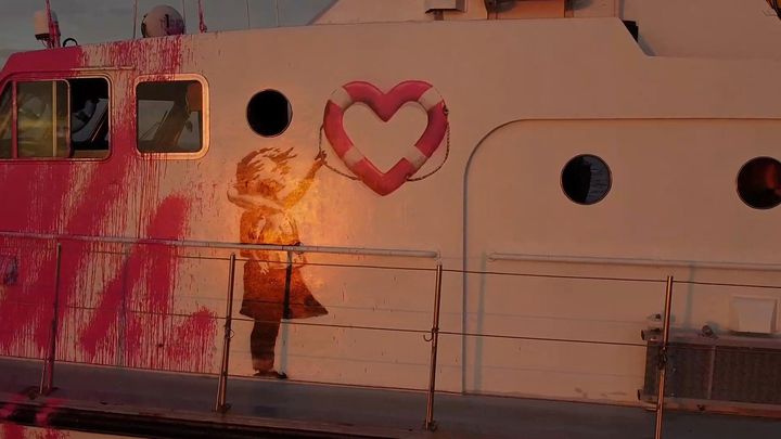 Le graffiti de Banksy réalisé sur le navire "Louise Michel", montrant une petite fille en gilet de sauvetage brandissant une bouée en forme de coeur. (HANDOUT  VIA REUTERS)