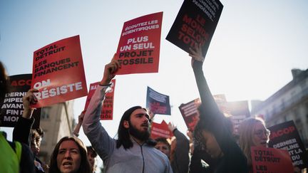 Des manifestants protestent en marge de l'assemblée générale de TotalEnergies, le 26 mars 2023 à Paris. (CLAIRE JAILLARD / HANS LUCAS / AFP)