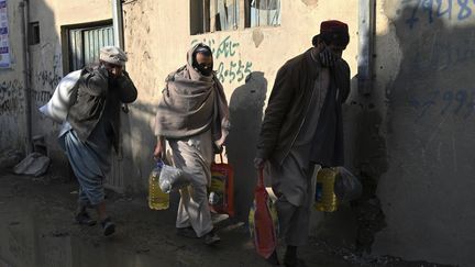 Des hommes viennent récupérer de l'aide humanitaire dans les faubourgs de Kaboul, le 30 janvier 2022.&nbsp;Les prévisions estiment que 97% d'Afghans vont souffrir de pauvreté (photo d'illustration). (WAKIL KOHSAR / AFP)