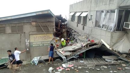 Des secouristes recherchent d'éventuelles victimes dans un bâtiment effondré après le séisme qui a frappé l'île de&nbsp;Mindanao (Philippines), dimanche 15 décembre 2019 à Padada.&nbsp; (SOCIAL MEDIA / REUTERS)