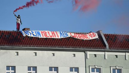 ​A Berlin, dans le district de Wedding, un(e) manifestante, juché(e) sur un toit, brandit un fumigène alors qu’en bas, dans la rue, plusieurs milliers de ses camarades défilent, le 30 avril 2017, contre un problème aigu dans la capitale allemande. Selon le journal «Bild», 3000 personnes, de gauche, ont manifesté la veille du 1er mai contre «la hausse des loyers et la transformation de la ville». Les autorités ont donc déclaré «la guerre à la gentrification». Ces dernières années, des milliers de Berlinois auraient été obligés de quitter leurs logements en raison de loyers devenus trop élevés. Certains squatteurs, mouvement très puissant dans les années 80, tentent de s’opposer au phénomène. En 2016, 125 policiers avaient été blessés lors d’une opération d’expulsion. (AFP - DPA - Britta Pedersen)