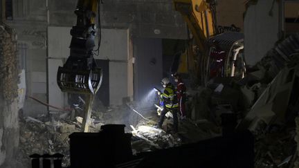 Les secouristes en pleines recherches au milieu des gravats de l'immeuble situé au 17 rue de Tivoli dans le 5e arrondissement de Marseille dimanche 9 avril au soir. (CLEMENT MAHOUDEAU / AFP)