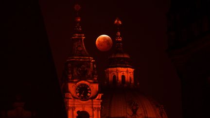 La lune rouge derrière l'église Saint Nicolas, à Prague, la capitale tchèque, le 21 janvier 2019. (MICHAL CIZEK / AFP)