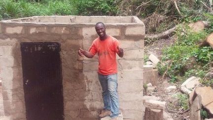 Ibrahima Tounkara devant le micro-barrage hydroélectrique qu'il a construit de ses mains dans son petit village de la région de Guéckédou (sud de la Guinée). (Guinéeinfos)