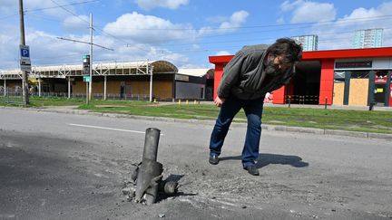 Un homme regarde une roquette plantée dans le sol à Kharkiv (Ukraine), le 21 avril 2021. (SERGEY BOBOK / AFP)