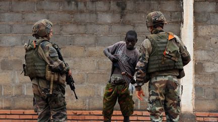 Deux soldats fran&ccedil;ais contr&ocirc;lent un homme dans le quartier PR4 de Bangui (Centrafrique), le 27 f&eacute;vrier 2014. (SIA KAMBOU / AFP)