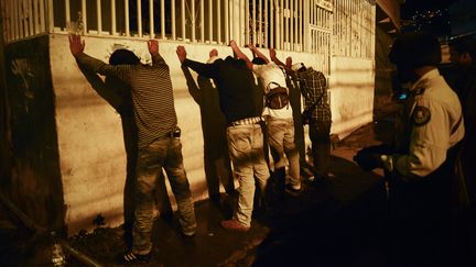 Un policier contrôle des hommes pendant une patrouille, dans le quartier pauvre de Petare, à Caracas (Venezuela), le 28 septembre 2012. (LEO RAMIREZ / AFP)