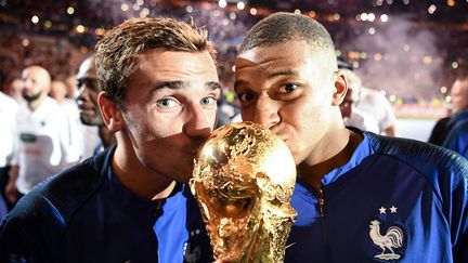 Antoine Griezmann (à gauche) et Kylian Mbappé embrassent le trophée qui récompense les vainqueurs de la Coupe du monde, le 9 septembre 2018 au Stade de France (Seine-Saint-Denis). (FRANCK FIFE / AFP)