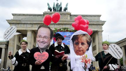 Une simulation de mariage entre le nouveau pr&eacute;sident fran&ccedil;ais Fran&ccedil;ois Hollande (2e G) et la chanceli&egrave;re allemande Angela Merkel (2e D) devant la porte de Brandebourg &agrave; Berlin (Allemagne) est organis&eacute;e par des activistes de l'Oxfam et d'Attac, le 7 mai 2012. (JOHN MACDOUGALL / AFP)