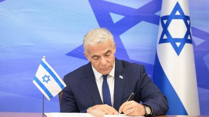 Le Premier ministre israélien Yaïr Lapid signant l'accord maritime entre le Liban et l'Etat hébreu, le 27 octobre 2022 à Jérusalem (Israël).&nbsp; (ISRAELI GOVT PRESS OFFICE (GPO) / ANADOLU AGENCY / AFP)