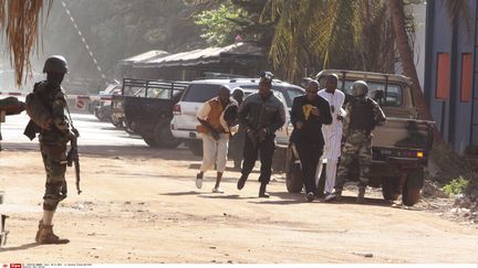 Des personnes s'éloignent en courant de l'hôtel Radisson, à Bamako, où se déroule une prise d'otages, le 20 novembre 2015. (HAROUNA TRAORE / AP / SIPA)