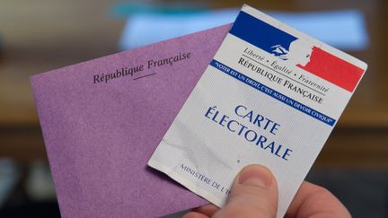 Un &eacute;lecteur tient sa carte &eacute;lectorale et son enveloppe au second tour de l'&eacute;lection l&eacute;gislative partielle dans le Doubs, le 8 f&eacute;vrier 2015. (SEBASTIEN BOZON / AFP)