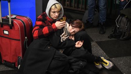 Deux personnes utilisent leur téléphone alors qu'elles se sont mises à l'abri dans une station de métro de Kiev (Ukraine), le 24 février 2022. (DANIEL LEAL / AFP)