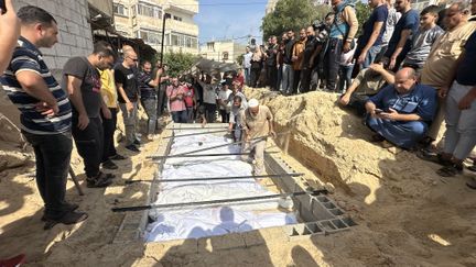 Des Palestiniens tués lors des attaques israéliennes sont enterrés dans une fosse commune dans un cimetière de Deir al-Balah, à Gaza, le 23 octobre 2023. (DOAA ALBAZ / ANADOLU / AFP)