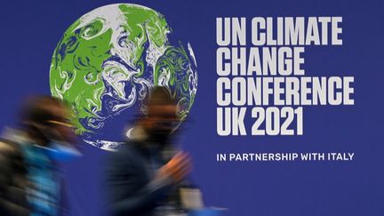 Deux personnes devant le logo de la COP26 à Glasgow (Royaume-Uni), le 2 novembre 2021. (PAUL ELLIS / AFP)