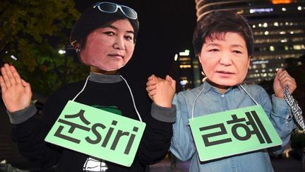 Des manifestants portent les masques des deux protagonistes lors d'une manifestation à Séoul le 27 octobre 2016. A droite la présidente de Corée du sud, Park Geun-Hye, à gauche son mentor Choi Soon-Sil. (AFP/ Jung Yeon-Je)