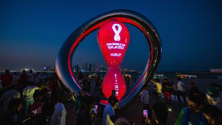 Une foule se rassemble pour prendre des photos près de l'horloge qui marque le compte à rebours avant la Coupe du monde à Doha au Qatar le 14 novembre 2022. (ANDREJ ISAKOVIC / AFP)