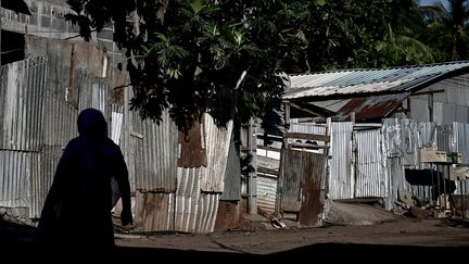 Une femme passe devant le bidonville du quartier "Talus 2" à Koungou, lors de son démantèlement dans le cadre de l'opération Wuambushu sur l'île française de Mayotte dans l'océan Indien, le 23 mai 2023. (PHILIPPE LOPEZ / AFP)