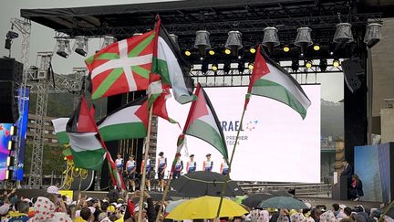 Des drapeaux basques et palestiniens sont agités au passage sur la scène de l'équipe Israel-Premier Tech, lors de la présentation des équipes du Tour de France 2023 à Bilbao. (Hortense Leblanc)