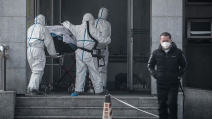 Le personnel hospitalier de l'hôpital de Jinyintan, à Wuhan en Chine, transportant un patient atteint du mystérieux virus similaire au Sras, le 18 janvier 2020. (STR / AFP)