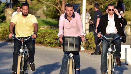 En juin 2017, quelques semaines après son élection,&nbsp;Emmanuel Macron fait du vélo dans les rues du Touquet (Pas-de-Calais), où le président et son épouse, Brigitte Macron, possèdent une résidence secondaire. Il est escorté par Alexandre Benalla, chargé d'assurer sa sécurité. (CHRISTOPHE ARCHAMBAULT / AFP)