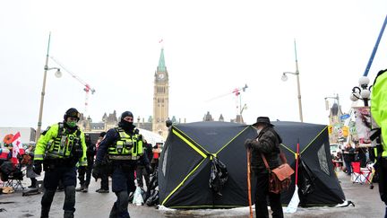 Des policiers passent à proxmité de manifestants du "convoi de la liberté, le 9 février 2022, à Ottawa (Canada). (KADRI MOHAMED / ANADOLU AGENCY / AFP)