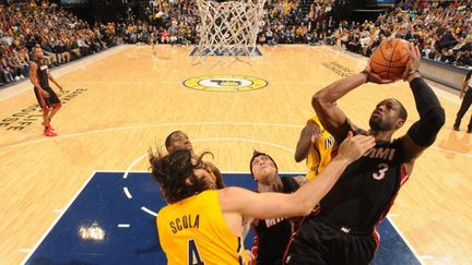 Dwyane Wade (Miami) en difficulté face à la défense de Luis Scola (Indiana) (RON HOSKINS / NBAE / GETTY IMAGES)