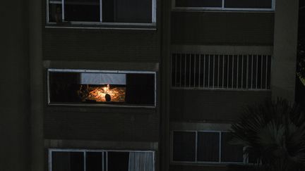 Dans cet immeuble de Caracas, seul un appartement est illuminé grâce à une bougie, le 10 mars. (MATIAS DELACROIX / AFP)