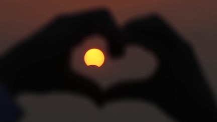 Un homme forme un c&oelig;ur avec ses doigts autour de l'&eacute;clipse solaire, au Koweit, le 3 novembre 2013. (YASSER AL-ZAYYAT / AFP)