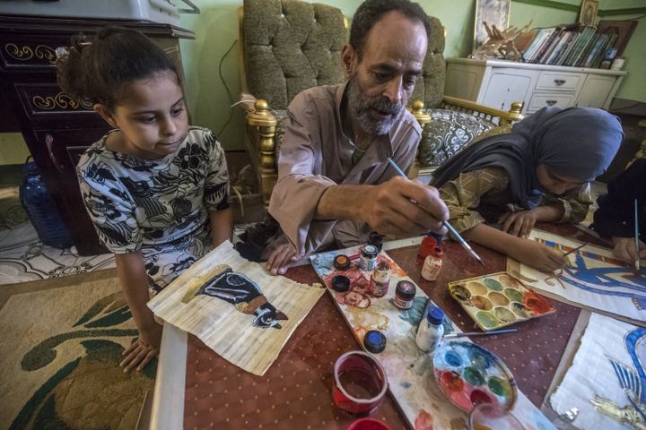 Le fermier et peintre Said Tarakhan dessine sur des feuilles de papyrus, chez lui, dans le village de al-Qaramous.&nbsp; (KHALED DESOUKI / AFP)