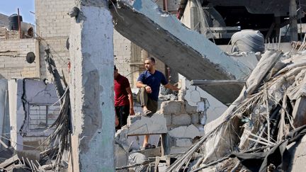 Des habitants de la bande de Gaza marchent dans les décombres, le 11 octobre 2023. (SAID KHATIB / AFP)