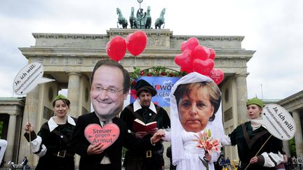 Des activistes allemands c&eacute;l&egrave;brent le faux mariage de Angela Merkel et Fran&ccedil;ois Hollande, le 7 mai 2012, pour r&eacute;clamer la mise en place d'une taxe sur les transactions financi&egrave;res. (JOHN MACDOUGALL / AFP)