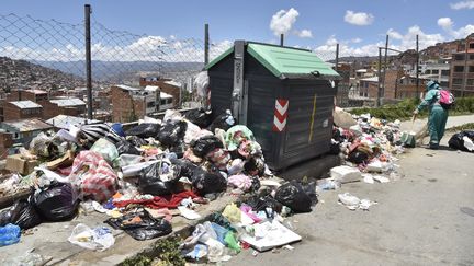 Un employé municipal ramasse des ordures autour d'un conteneur dans une rue de La Paz, en Bolivie, le 21 janvier 2019.&nbsp; (AIZAR RALDES / AFP)