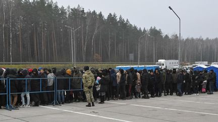 Des réfugiés patientent à la frontière entre la Biélorussie et la Pologne, le 17 novembre 2021. (VIKTOR TOLOCHKO / SPUTNIK / AFP)