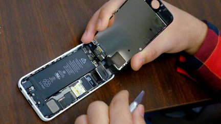 Un homme répare un iPhone de la marque Apple dans un magasin de New York (Etats-Unis), le 17 février 2016. (EDUARDO MUNOZ / REUTERS)