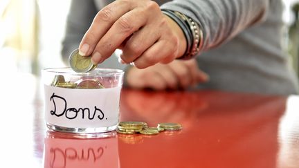 Un homme fait un don de pièces de monnaie. Photo d'illustration. (SYLVIE CAMBON / MAXPPP)