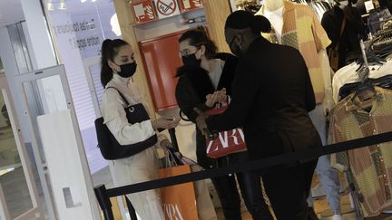 Des clientes reçoivent une dose de gel hydroalcoolique dans un magasin parisien, le 19 mai 2021. (ESTELLE RUIZ / HANS LUCAS / AFP)