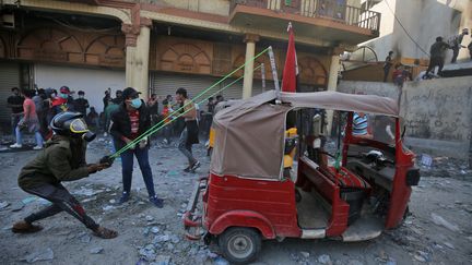 Des manifestants lancent des pierres sur les forces de sécurité lors de heurts, à Bagdad, le 26 novembre 2019.&nbsp; (AHMAD AL-RUBAYE / AFP)