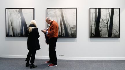 Des visiteurs observent les clichés du photographe sud-coréen Bae Biden à Paris Photo en 2019.&nbsp; (FRANCOIS GUILLOT / AFP)