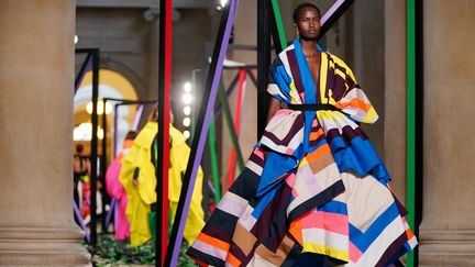 Une robe spectaculaire, crinoline de superpositions multicolores, du défilé de la créatrice Roksanda au British Museum, faisait face à la même robe sur un écran numérique, qui habillera les avatars du métavers. London Fashion Week, le 21 février 2022.&nbsp; (JONATHAN BRADY / MAXPPP)