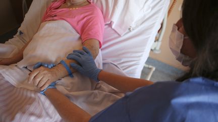 Une infirmière et une patiente dans une unité de soins palliatifs à Ajaccio (Corse-du-Sud), le 23 avril 2020. (PASCAL POCHARD-CASABIANCA / AFP)