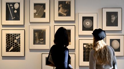 Des personnes regardent des photographies de l'artiste Man Ray lors d'une présentation d'une collection d'œuvres par la maison d'enchères Christie's à Paris, le 14 mars 2022 (EMMANUEL DUNAND / AFP)