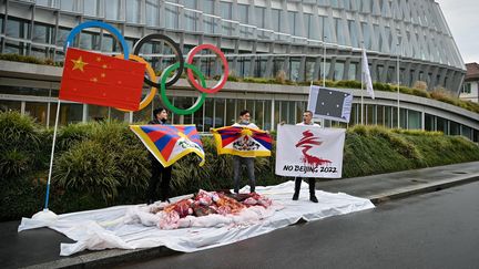 Des militants de l'International Tibet Network (Réseau international pour le Tibet) tiennent des drapeaux du Tibet devant le siège du CIO lors d'une manifestation contre les Jeux olympiques d'hiver de Pékin 2022, le 3 février 2021 à Lausanne.&nbsp; (FABRICE COFFRINI / AFP)