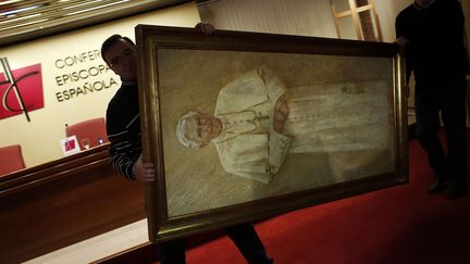 Des ouvriers d&eacute;crochent un portrait du pape Beno&icirc;t XVI apr&egrave;s la conf&eacute;rence de presse du&nbsp;cardinal Antonio Maria Rouco Varela donn&eacute;e &agrave; la suite de l'annonce de la r&eacute;signation du souverain pontif, Madrid (Espagne), le 11 f&eacute;vrier 2013. (SUSANA VERA / REUTERS)