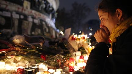 Une jeune femme se recueille place de la République, à Paris, le 16 novembre 2015. (CHRISTIAN HARTMANN / REUTERS)